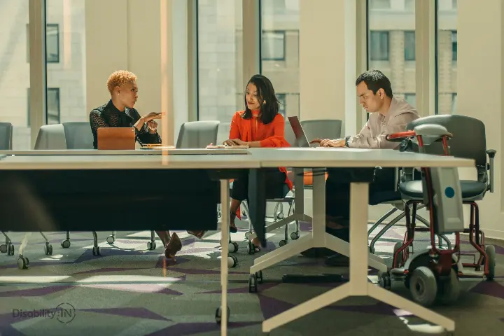 Two people having a conversation about an idea, with one working on a separate concern. They appear confident and have a calm expression on their face.